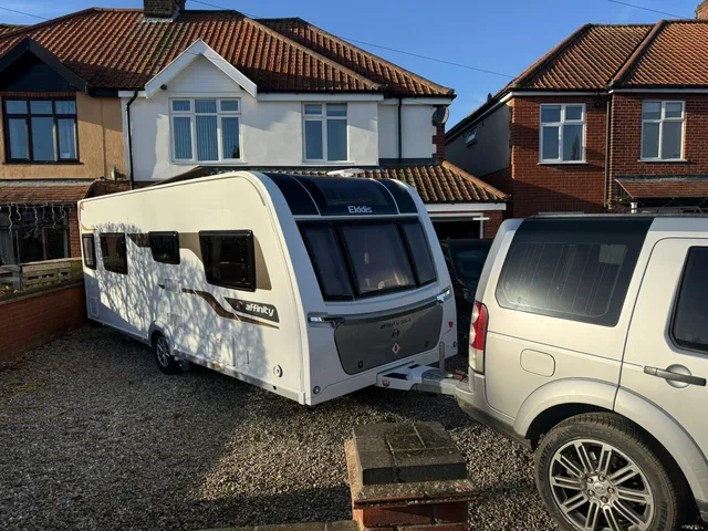 Touring caravan on a gravel driveway beside a tow vehicle