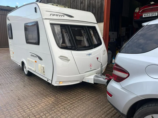 Touring caravan hitched to a tow vehicle on a paved forecourt