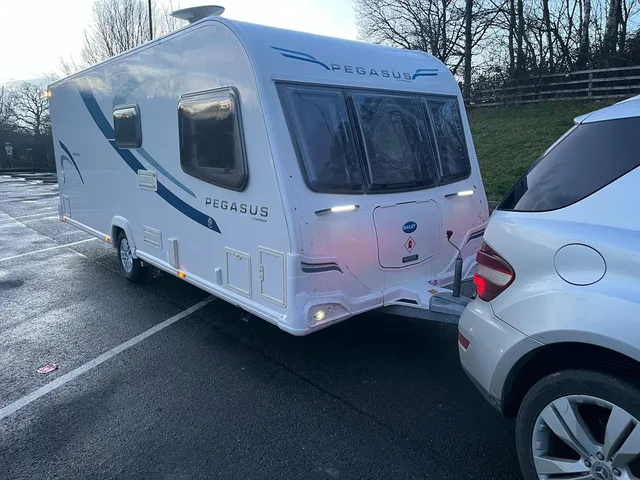 Touring caravan and tow vehicle on a wet paved area