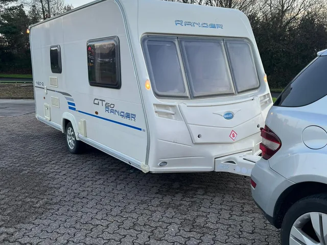 Touring caravan beside a tow vehicle on a block paved area