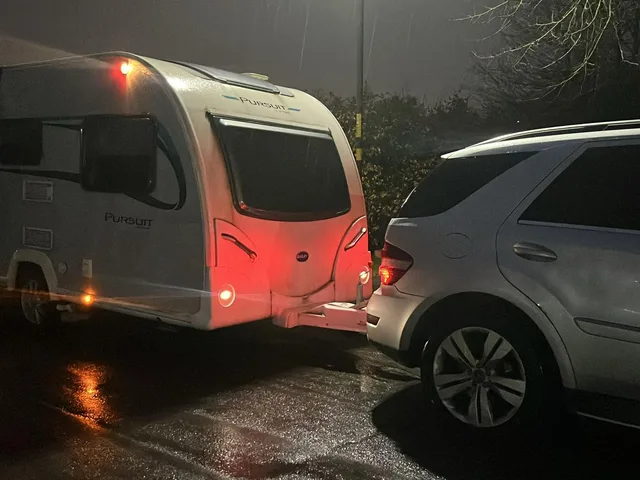 Caravan and tow vehicle with lights on after dark