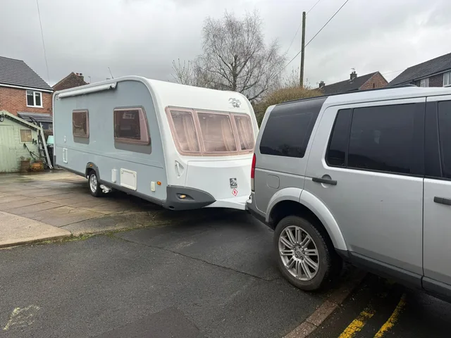 Touring caravan hitched to a tow vehicle beside a residential street